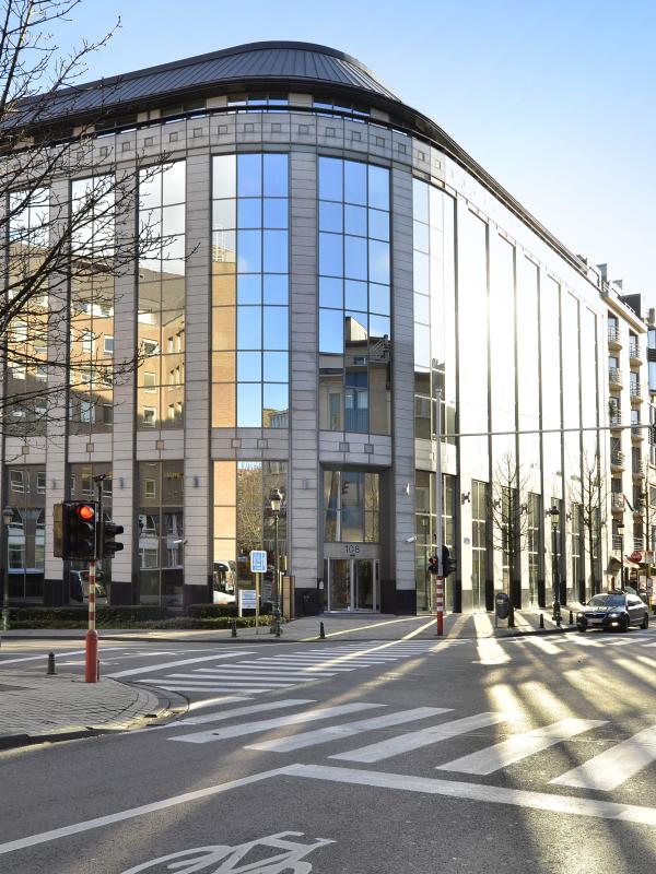 Außenansicht eines modernen Eckgebäudes mit vielen Fenstern an einer Straßenkreuzung.