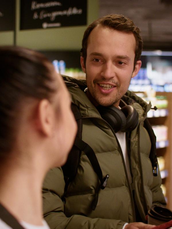 Ein Mann unterhält sich im Supermarkt mit einer Mitarbeiterin