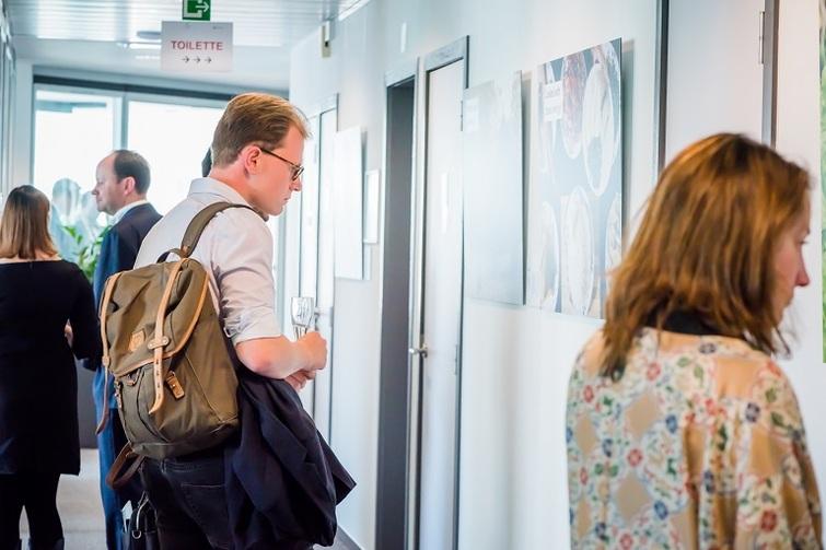 Personen stehen vor Gemälden und schauen sich diese an