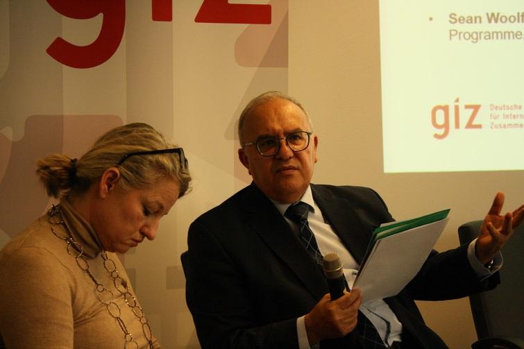 Mann schaut nach vorne. Frau die links von ihm sitzt schaut nach unten