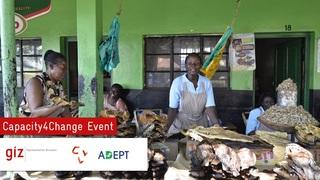 Personen stehen vor einem grünen Gebäude. Auf dem Bild steht "Capacity4Change Event"