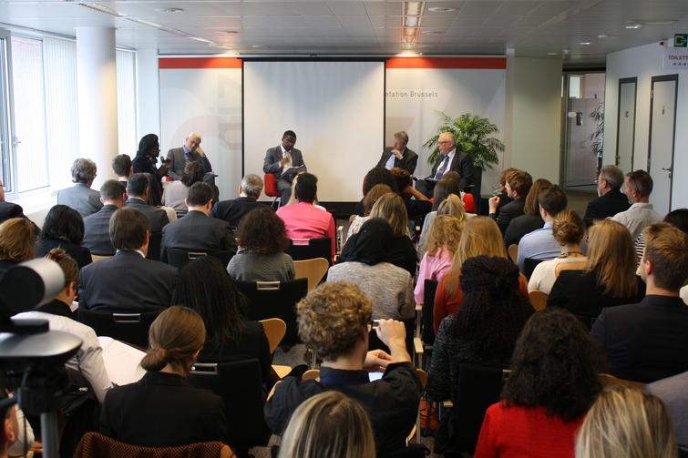 4 Männer sitzen auf Stühlen vor einem Publikum