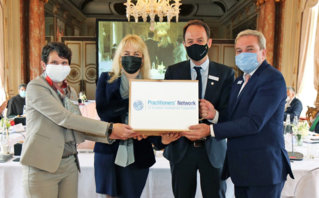 Vier Personen mit Gesichtsmasken halten ein Schild hoch