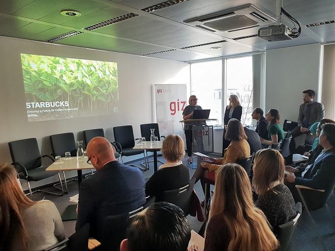 Eine Frau steht vorne an einem Pult und spricht zu einem Publikum