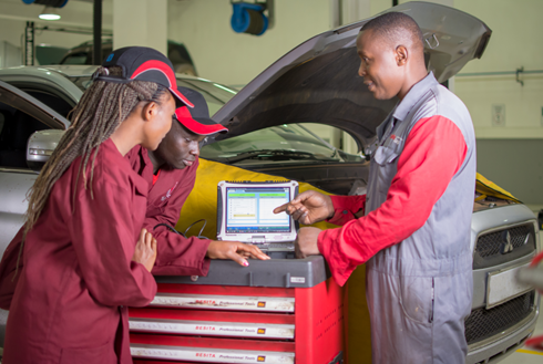 A group of people standing next to a computer.