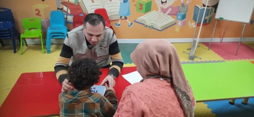 A GIZ employee sits with a boy and his mother in a kindergarten.