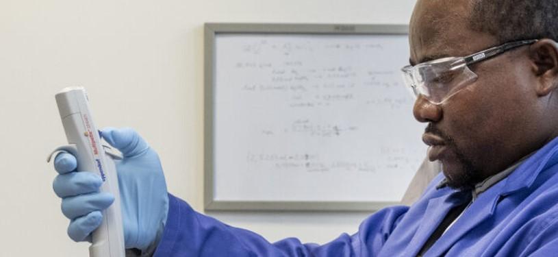 A man in a laboratory holds a measuring device in his hand.