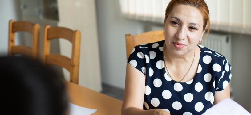 Silvia Feraru sitzt an einem Tisch und hat Papiere in der Hand.