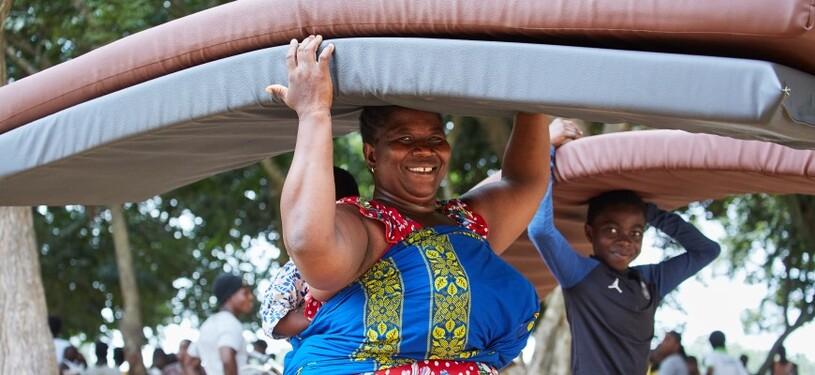 A woman and a boy carrying mattresses on their heads