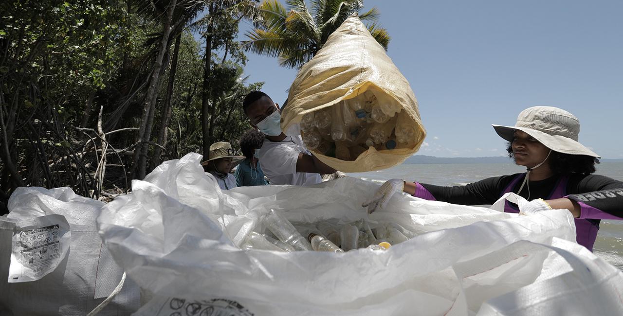 A man dumps collected rubbish into a rubbish bag.