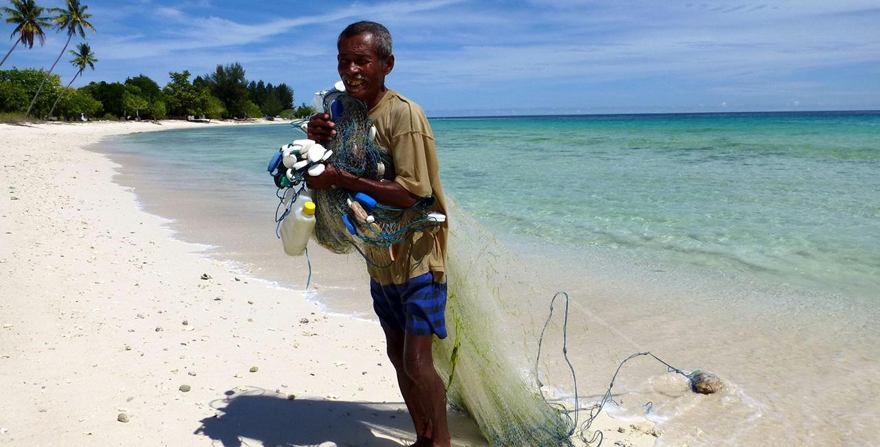 A man collects rubbish on the beach.