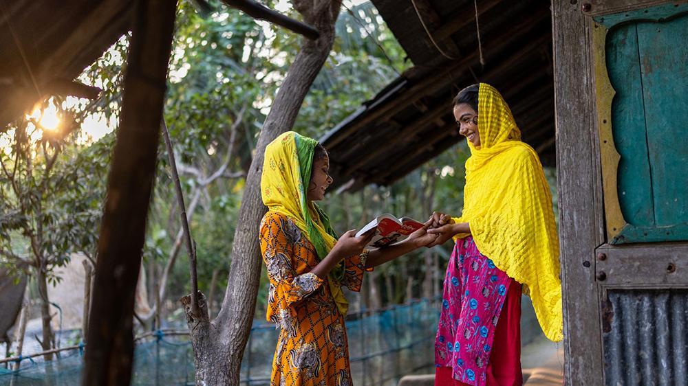 Two women holding a book