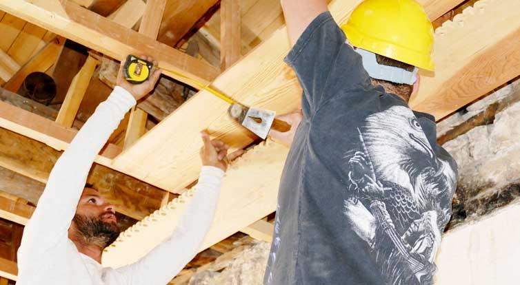 Zimmerleute vermessen die Holzdecke.