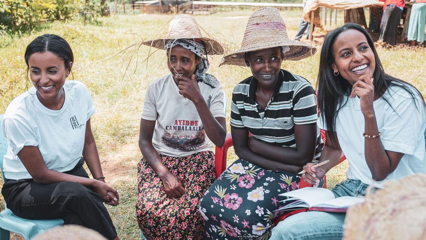 Vier Frauen sitzen, reden und lächeln