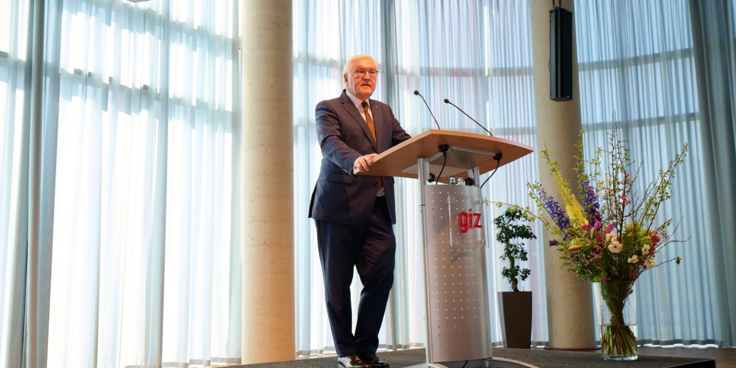 Mr. Steinmeier at the lectern on the podium. A vase of flowers is on his right.