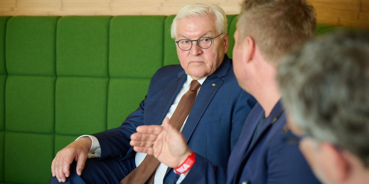 Mr. Steinmeier and Mr. Schäfer-Gümbel in conversation with GIZ employees, sitting around a table with drinks.