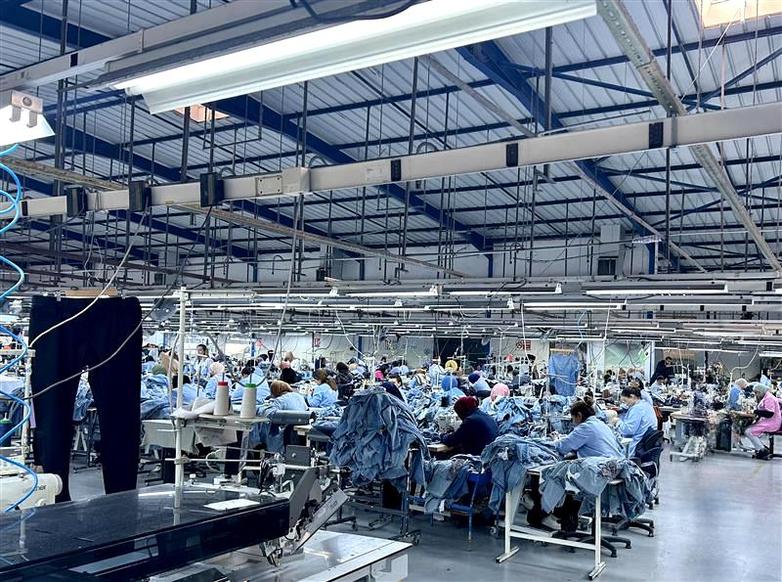A factory with lots of people in blue suits, busy at various work stations.