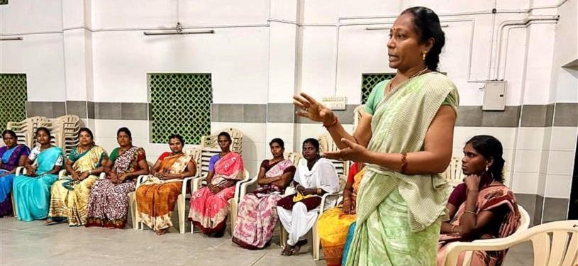 Eine Gruppe von Frauen, die bei einer art Vortrag in einer Halle im Kreis sitzen.