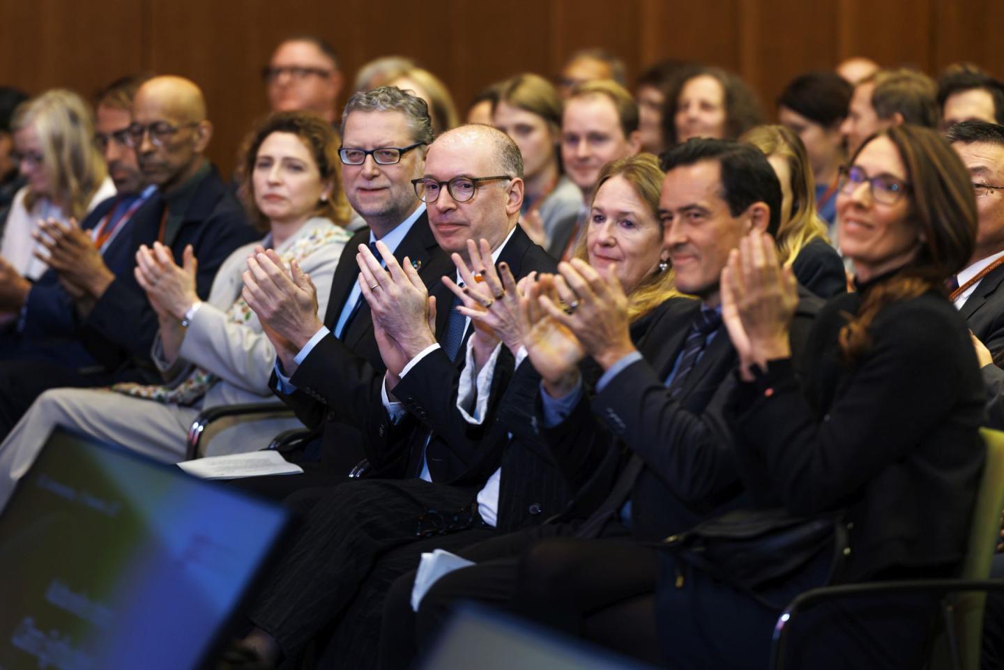 Several persons sitting in a row, clapping