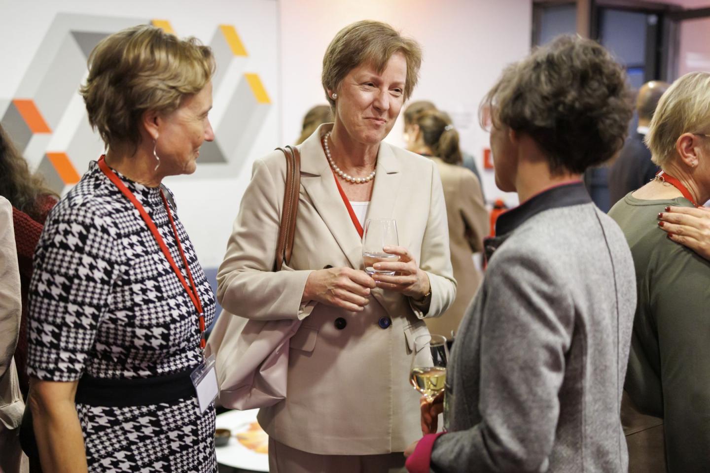 Drei Frauen stehen beieinander, eine redet, zwei hören zu