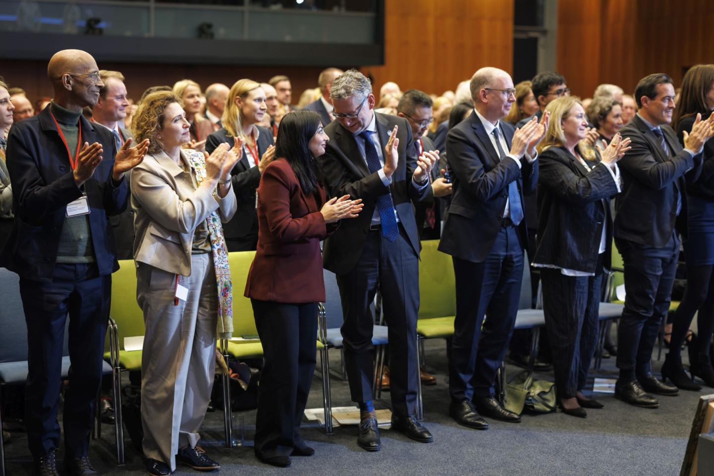 Mehrere Menschen stehen nebeneinander und klatschen bzw. reden miteinander