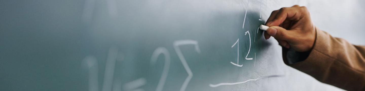 Une personne écrit des chiffres sur un tableau avec une craie.