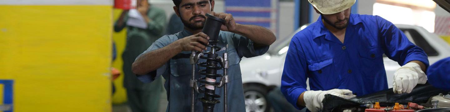 Zwei Automechaniker arbeiten in einer Autowerkstatt.