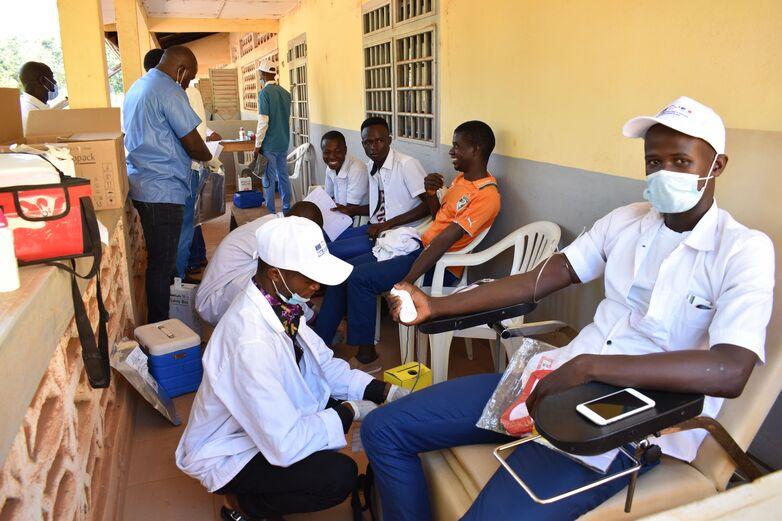 Junge Männer sitzen auf einer Veranda und spenden Blut.