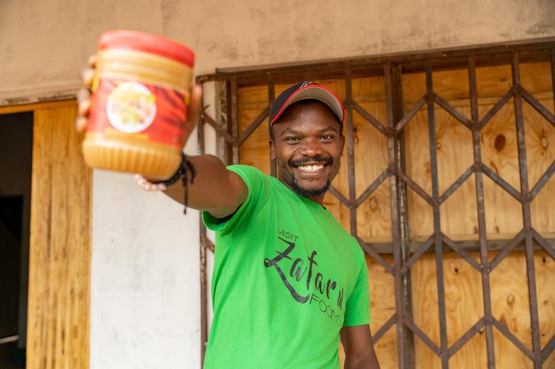 A man holding out a jar of peanut butter.