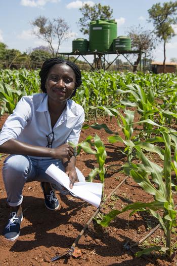 A woman crouching in a field.