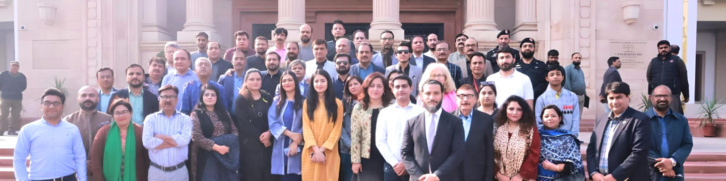 Eine Menschengruppe vor einem säulengetragenen Eingangsportal.