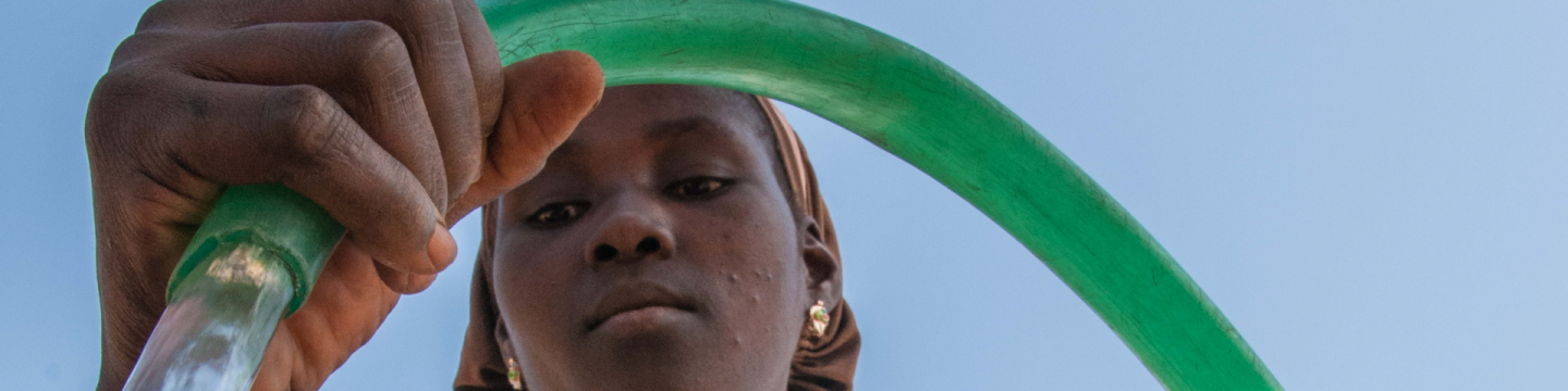Ein Mädchen schöpft Wasser aus einem öffentlichen Brunnen.