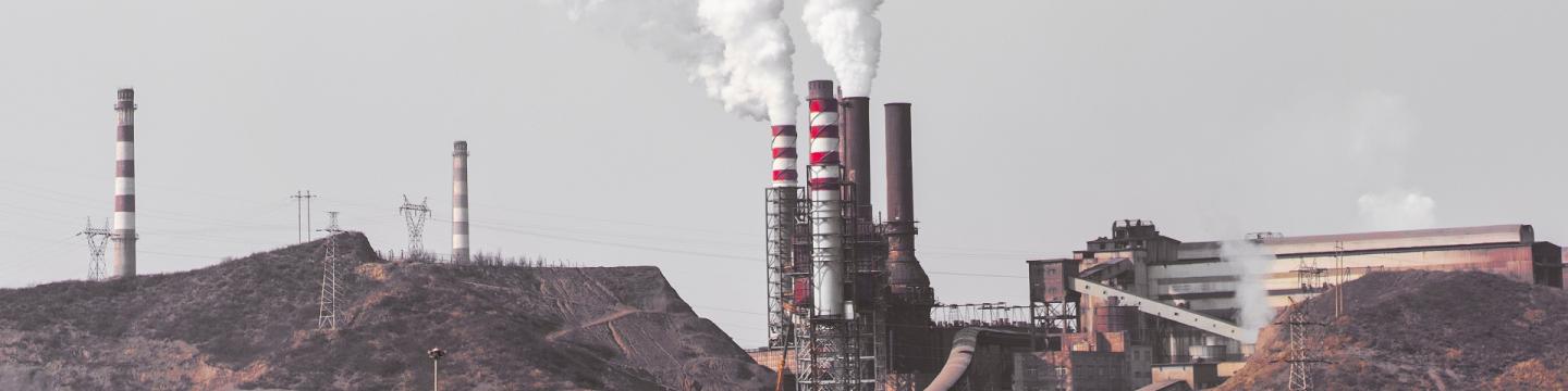 Труби промислової установки випускають білий дим у небо.