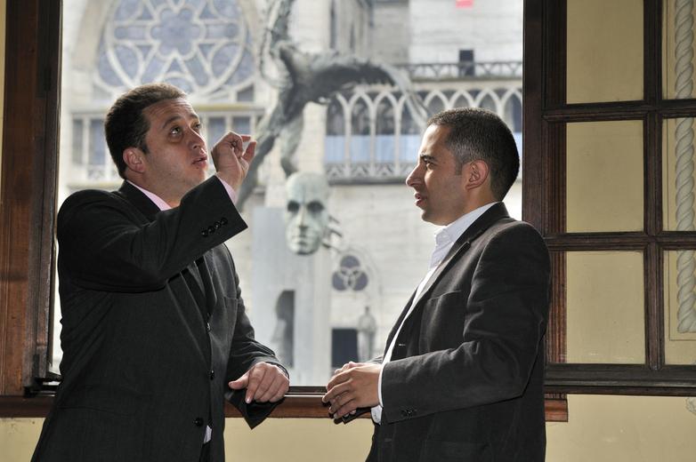 Dos hombres con traje hablan gesticulando.