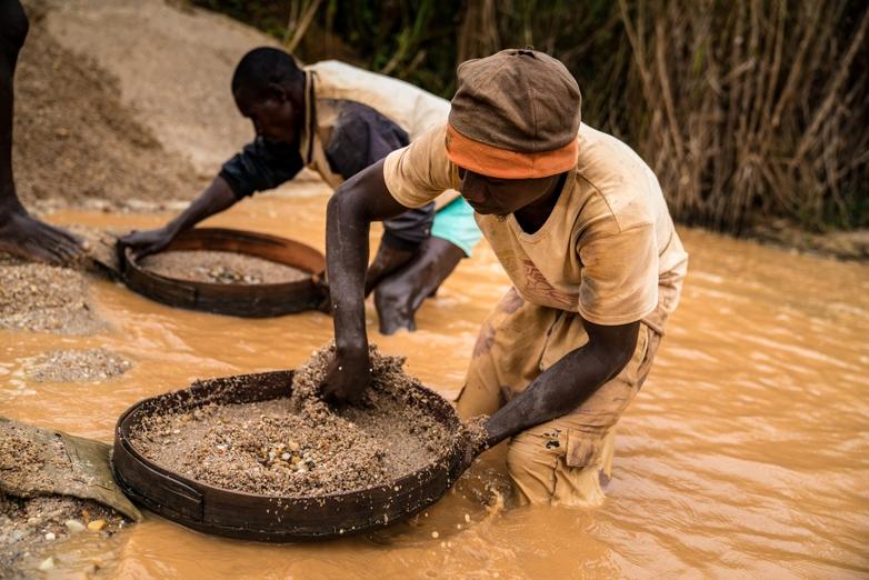 Deux jeunes hommes tamisent un cours d’eau pour trouver des diamants. Copyright : GIZ / Michael Duff