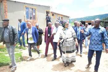 Mehrere Personen besichtigen ein hybrides Solar-Wind-Energie Mini-Grid System in Upper Blinkwater, Südafrika.