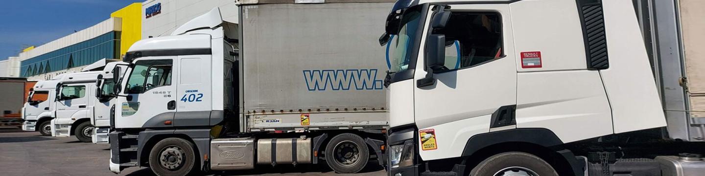 Mehrere LKW parken vor einer Lagerhalle.