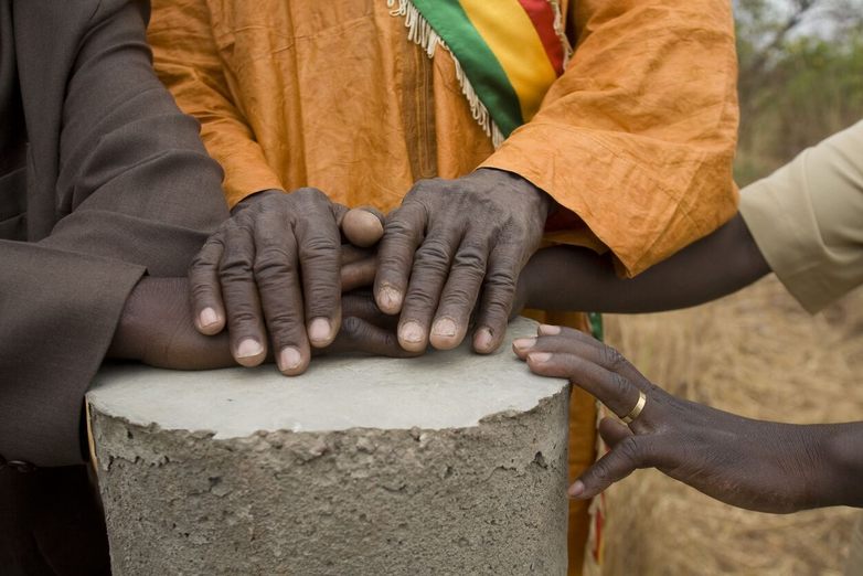 Close-up of hands on a concrete cylinder.