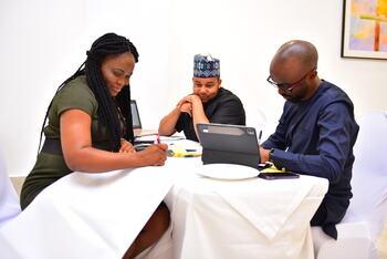 Drei Teilnehmende des Bootcamp Trainings sitzen am Tisch und erarbeiten ein Geschäftsmodell.