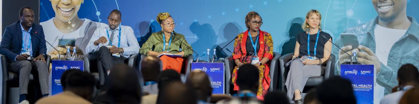 Vier Personen sitzen bei einer Podiumsdiskussion auf einer Bühne.