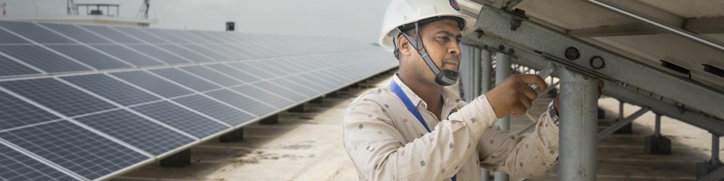 Ein Mann schraubt an einer Photovoltaikanlage. © GIZ BD/Rizwan Hasan