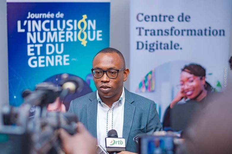 A man holds a microphone and speaks into a camera at an event on digital inclusion. Copyright: GIZ