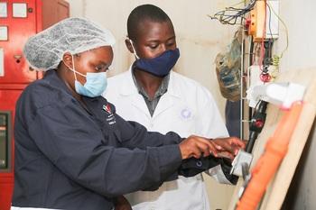A trainee in Industrial Mechatronics is shown by one of the industry mentors at Capwell Industries how to make a two-way light switch during her industrial training. GIZ/AnchorBay