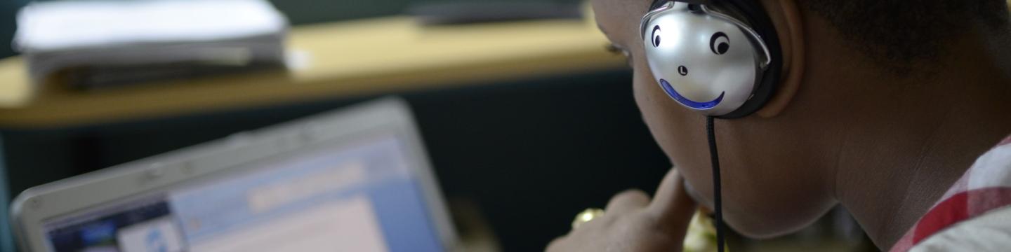 Ein Junge mit Kopfhörern sitzt vor einem Laptop.