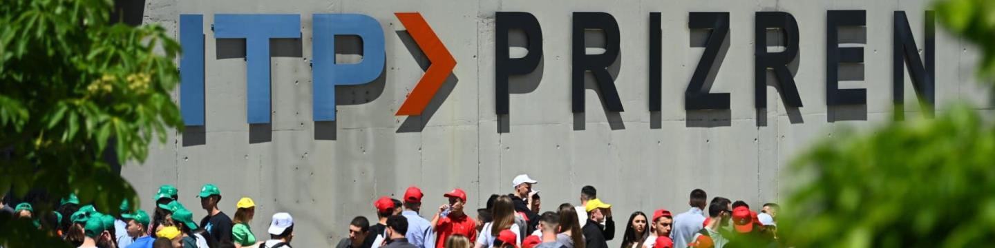 Menschen stehen vor einer Wand, auf der "ITP Prizren" steht.