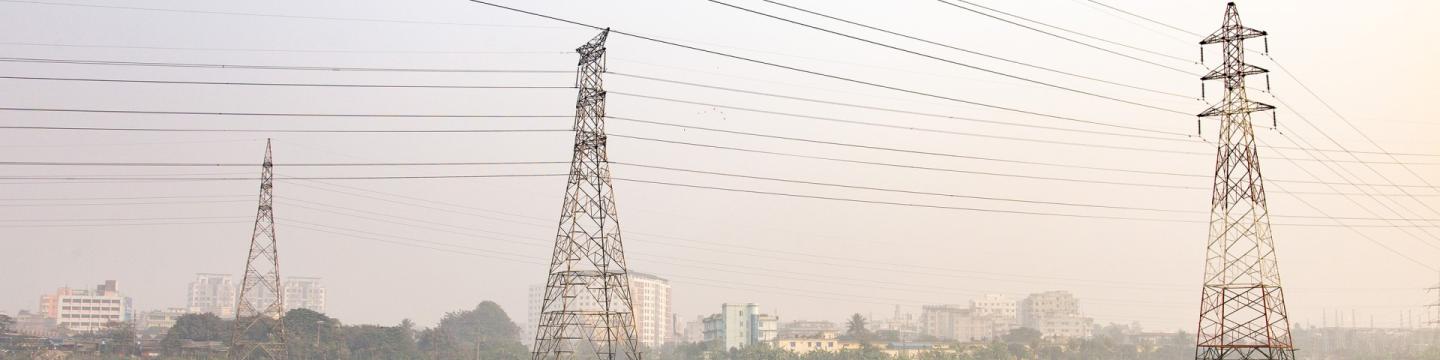 Drei Masten einer Hochspannungsleitung auf einem Feld.
