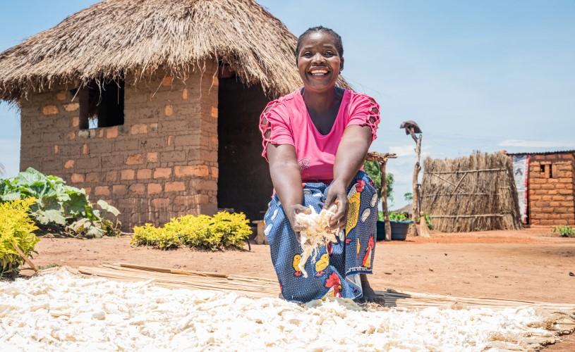 A woman holds beans up to the camera and smiles.