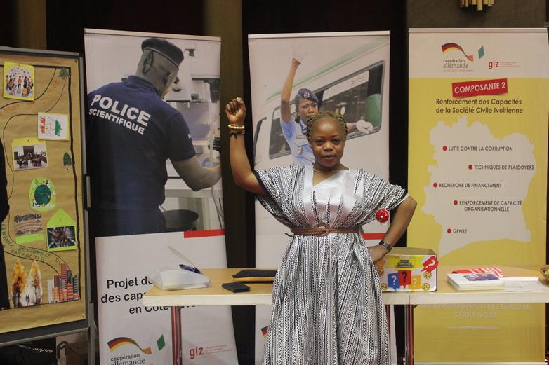 Une femme lève le poing devant un stand d’information du projet.