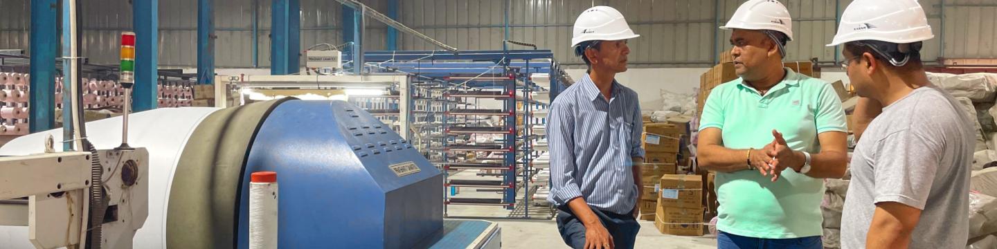 Drei Männer in Schutzhelmen stehen um eine Maschine.