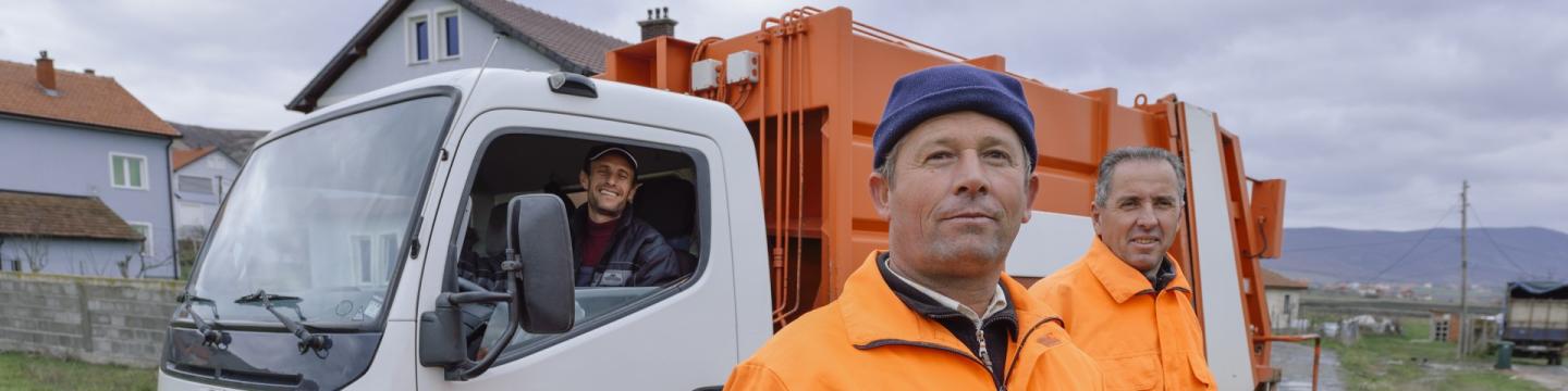 Drei Arbeitskräfte mit einem Kraftfahrzeug.